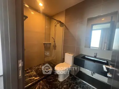 Modern bathroom with sleek design, featuring a glass shower enclosure and elegant fixtures.