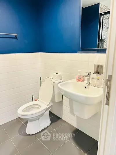 Modern bathroom with blue walls, white tiles, and sleek fixtures.