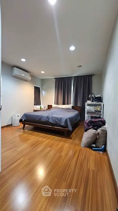 Spacious bedroom with wooden flooring and modern decor in a cozy apartment.