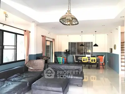 Spacious living room with modern decor and ample natural light, featuring a stylish sectional sofa and dining area.