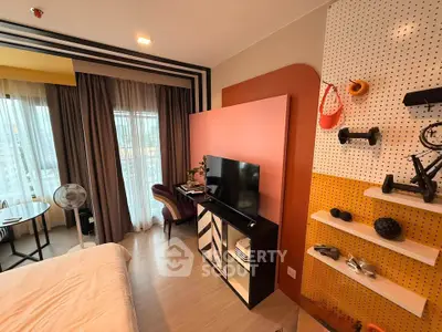 Stylish modern bedroom with vibrant decor and city view, featuring a cozy seating area and entertainment setup.