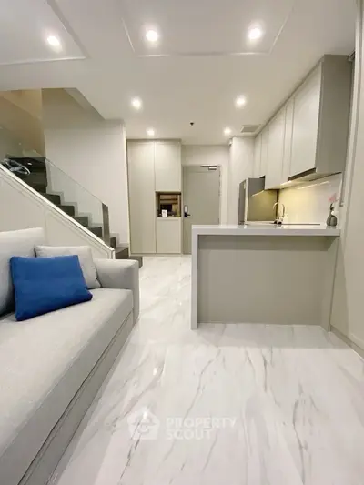 Modern open-plan living room with sleek kitchen and elegant staircase