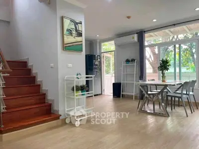 Spacious modern living room with dining area and large windows overlooking greenery.