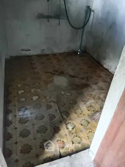Unfinished room with vintage floral tile flooring, potential for renovation.