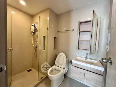 Modern bathroom with glass shower and sleek vanity in contemporary apartment.