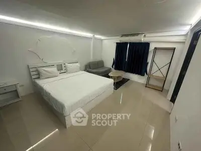 Spacious modern bedroom with sleek design and cozy seating area.