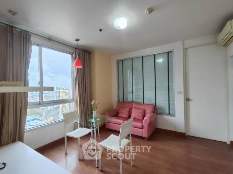 Bright living room with city view, featuring a cozy pink sofa and modern dining area.