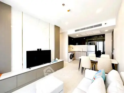 Modern living room with open kitchen, featuring sleek furniture and appliances.