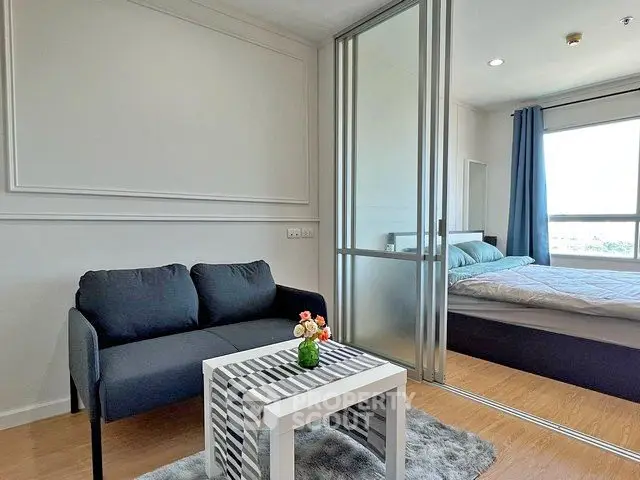 Modern studio apartment with cozy living area and bedroom separated by glass partition.