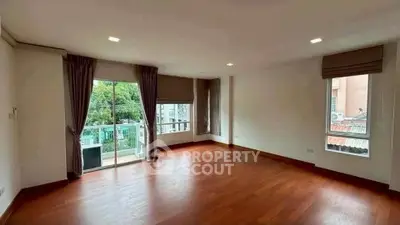Spacious empty living room with hardwood floors and large windows for natural light.