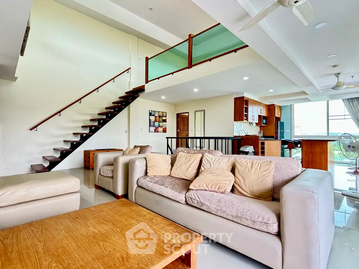 Spacious modern living room with open layout and stylish staircase in a luxury apartment.