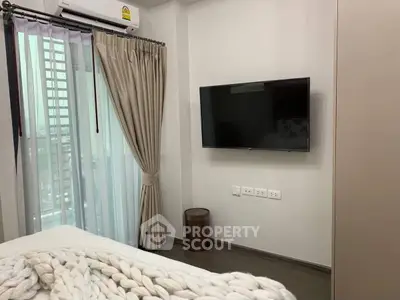 Modern bedroom with wall-mounted TV and large window with city view.