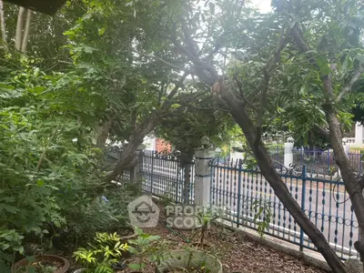 Charming garden view with lush greenery and decorative fence in a serene neighborhood.