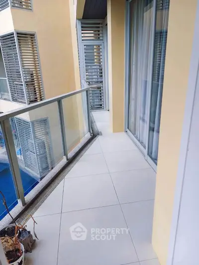 Modern apartment balcony with glass railing and pool view