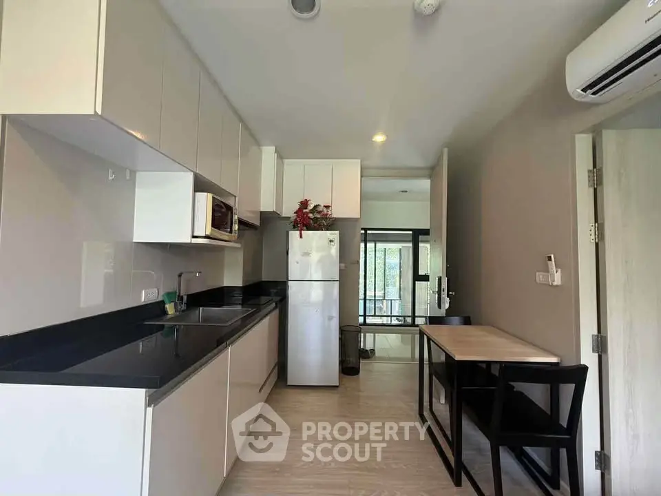 Modern kitchen with sleek cabinetry and dining area in a stylish apartment.