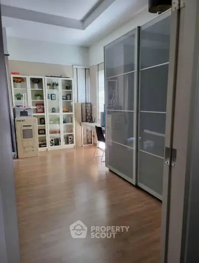 Spacious study room with modern sliding door wardrobe and wooden flooring