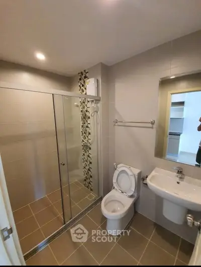 Modern bathroom with glass shower enclosure and sleek fixtures in a contemporary apartment.