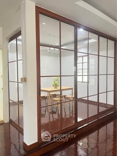Modern glass-enclosed study room with wooden flooring and elegant decor