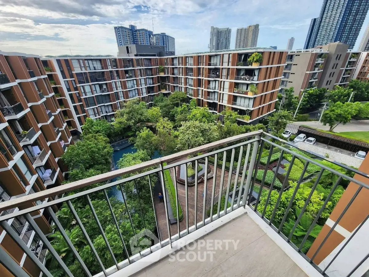Stunning view from balcony overlooking lush garden and modern apartment complex