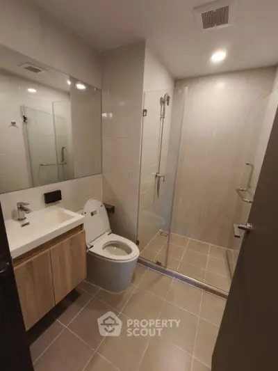 Modern bathroom with sleek design, featuring a glass shower and contemporary fixtures.
