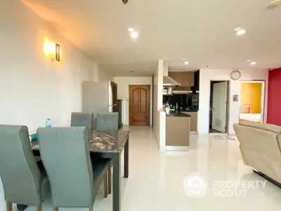 Spacious open-plan living area seamlessly connecting to a modern kitchen with ample counter space, highlighted by natural light and tasteful decor.