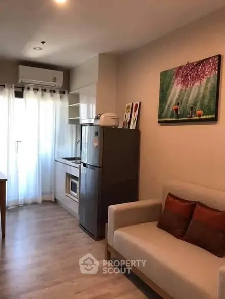 Cozy living room with kitchenette and modern decor in a compact apartment.