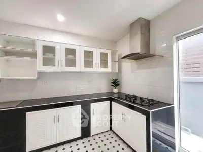 Modern kitchen with sleek black countertops and white cabinets, featuring a gas stove and stylish backsplash.