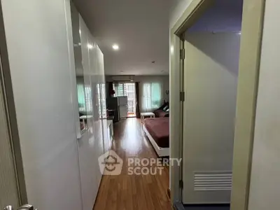 Spacious bedroom with wooden flooring and modern furnishings in a cozy apartment.