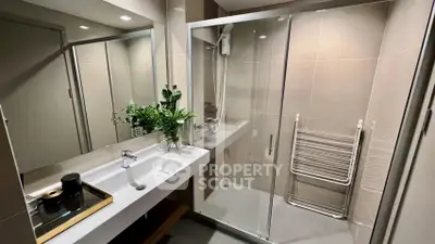 Modern bathroom with glass shower and sleek vanity in stylish apartment.