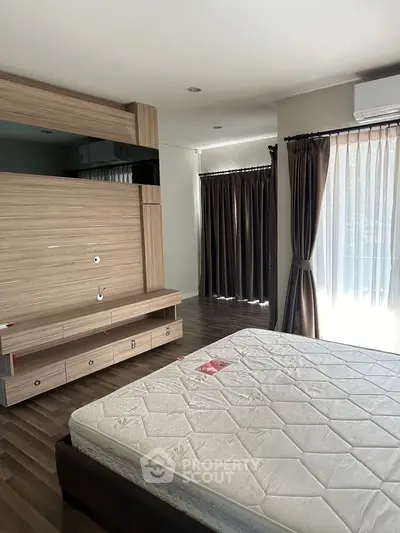 Spacious bedroom with modern wooden accents and large windows for natural light.