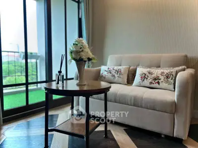 Cozy living room with elegant sofa and floral decor near large window.