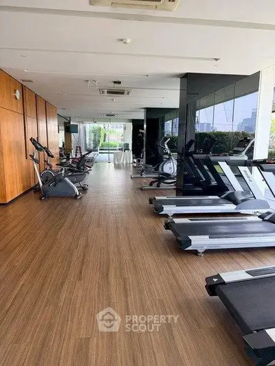 Spacious modern gym with state-of-the-art equipment and city view, perfect for fitness enthusiasts.