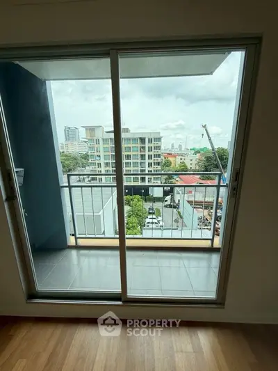 Modern apartment balcony with city view through sliding glass doors.