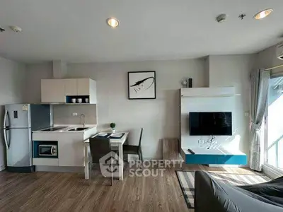 Modern open-plan living room with kitchen, featuring sleek appliances and stylish decor.