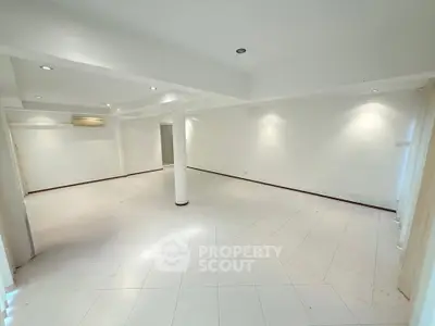 Spacious open-plan living area with modern lighting and tiled flooring.