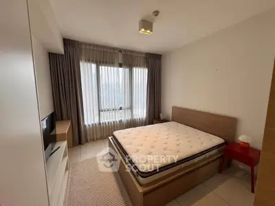Modern bedroom with large window, stylish bed, and cozy decor in a bright apartment.