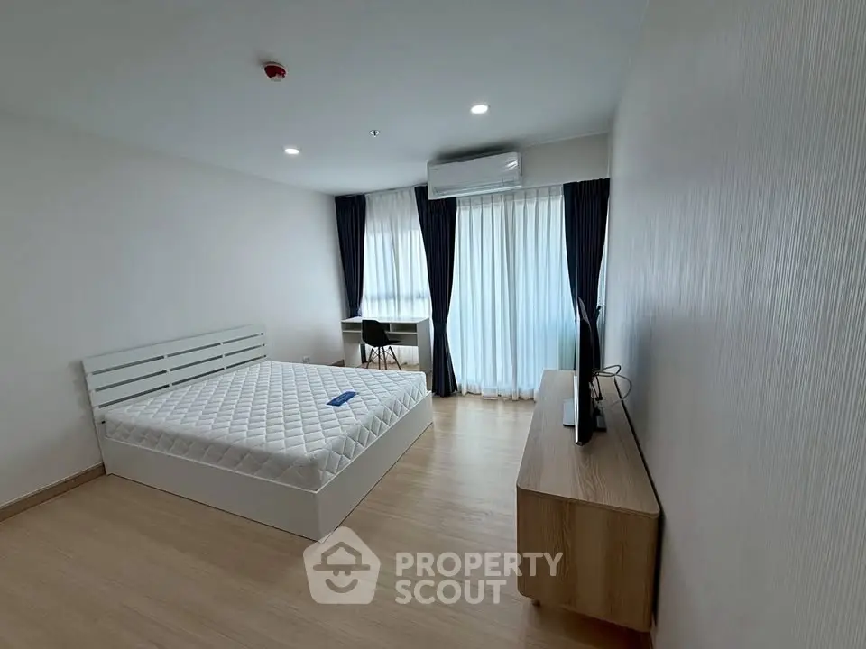 Spacious bedroom with modern furnishings and large windows for natural light.