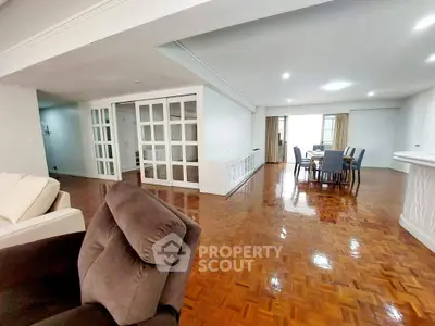 Spacious open-plan living and dining area with polished wooden floors and modern furnishings.