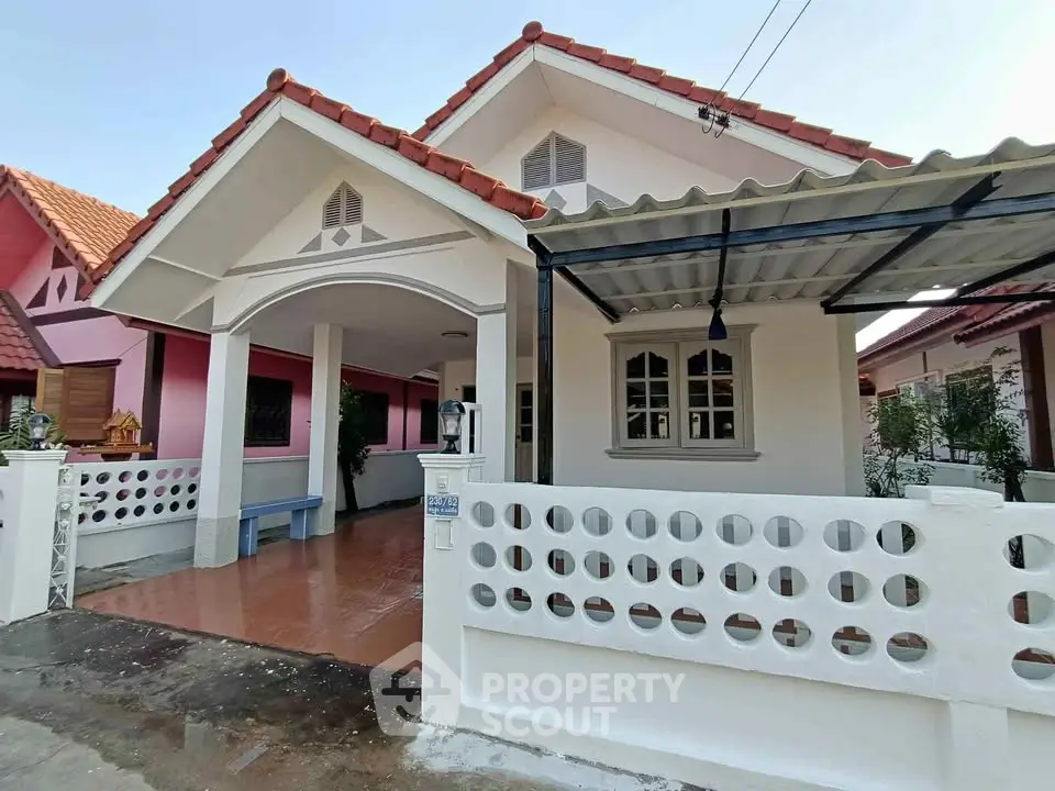 Charming single-story house with tiled roof and spacious carport in a serene neighborhood.