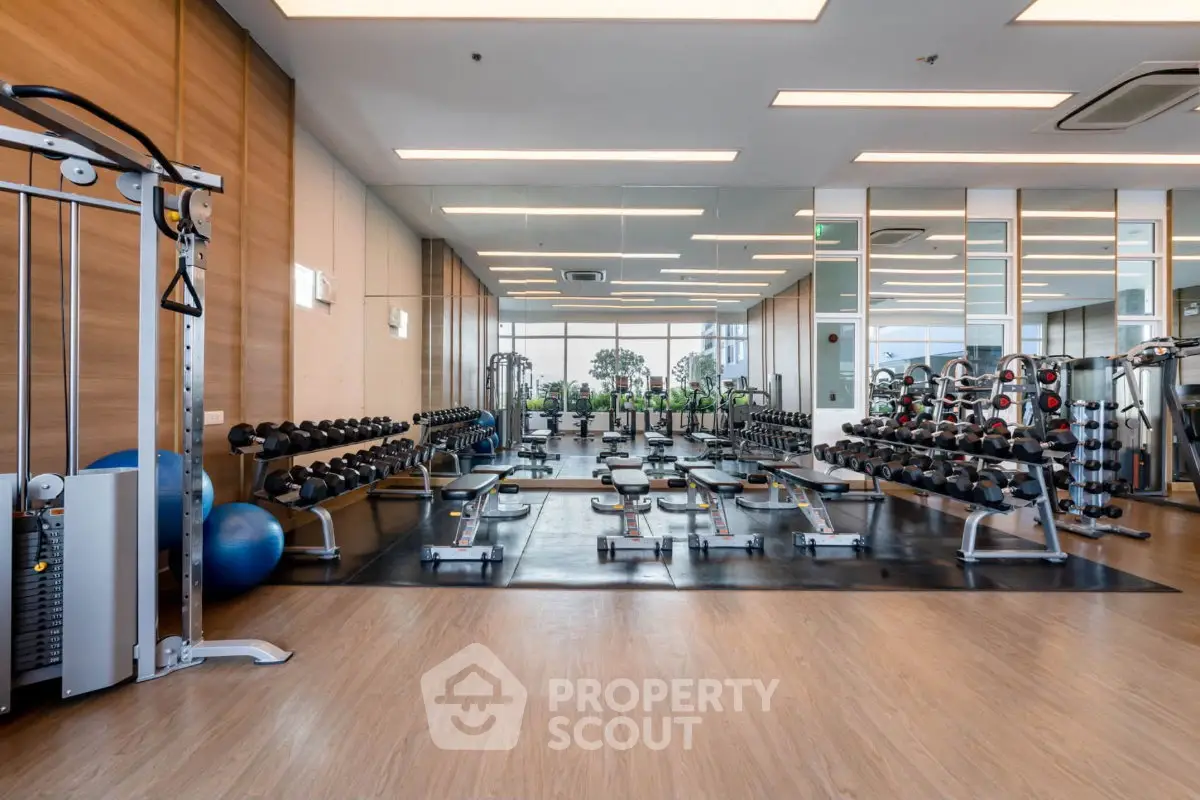 Spacious modern gym with state-of-the-art equipment and mirrored walls in luxury building.