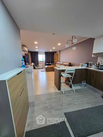 Spacious open-plan living room with modern kitchen and stylish decor, perfect for entertaining.