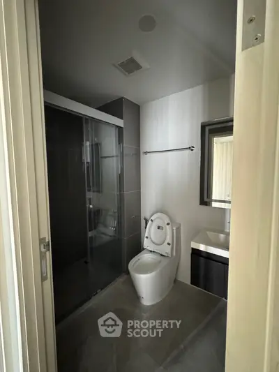 Modern bathroom with sleek design, featuring a glass-enclosed shower and contemporary fixtures.