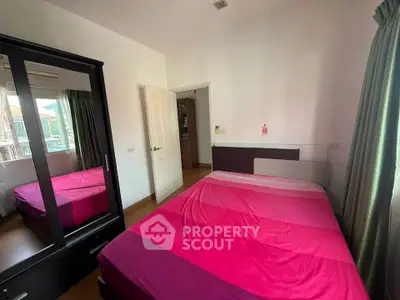 Cozy bedroom with vibrant pink bedding and ample natural light from window.