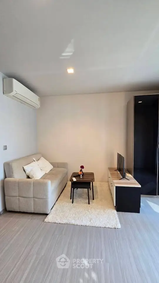 Modern living room with cozy sofa, air conditioning, and sleek TV setup in a stylish apartment.
