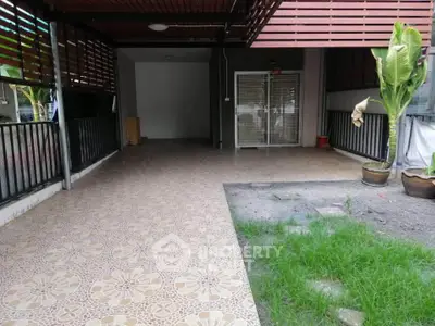 Spacious covered patio with tiled flooring and garden view, perfect for outdoor relaxation.