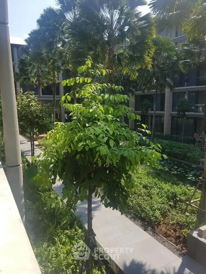 Lush garden view in modern residential complex with palm trees and landscaped pathways.