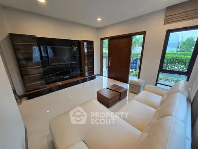Spacious modern living room with sleek furniture and large TV, offering a cozy and stylish ambiance.