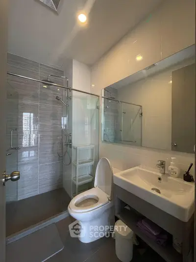 Modern bathroom with glass shower and sleek fixtures in contemporary apartment.