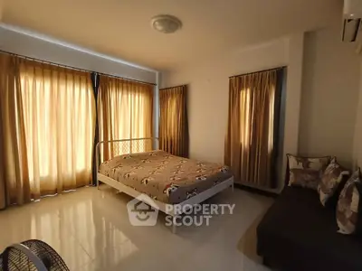 Spacious bedroom with cozy decor and ample natural light from large windows.
