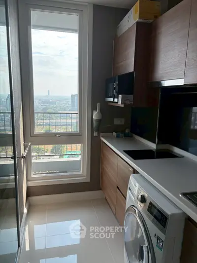 Modern kitchen with city view, sleek cabinetry, and built-in appliances in high-rise apartment.